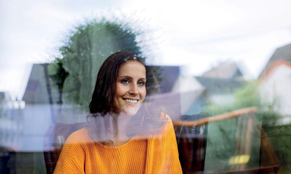 Young woman sitting laughing behind a window.